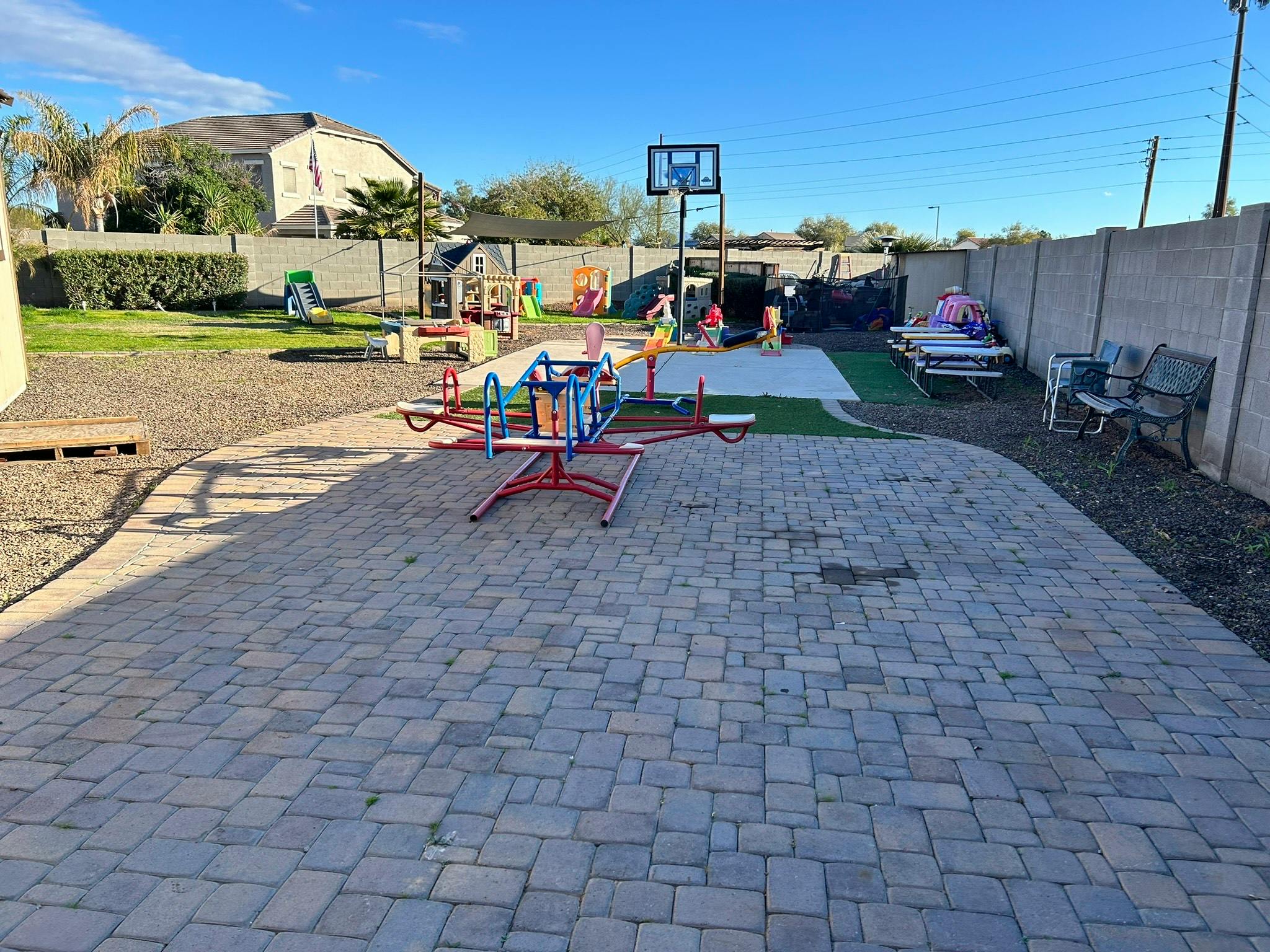 Outdoor playground with a merry-go-round, basketball hoop, and picnic table
