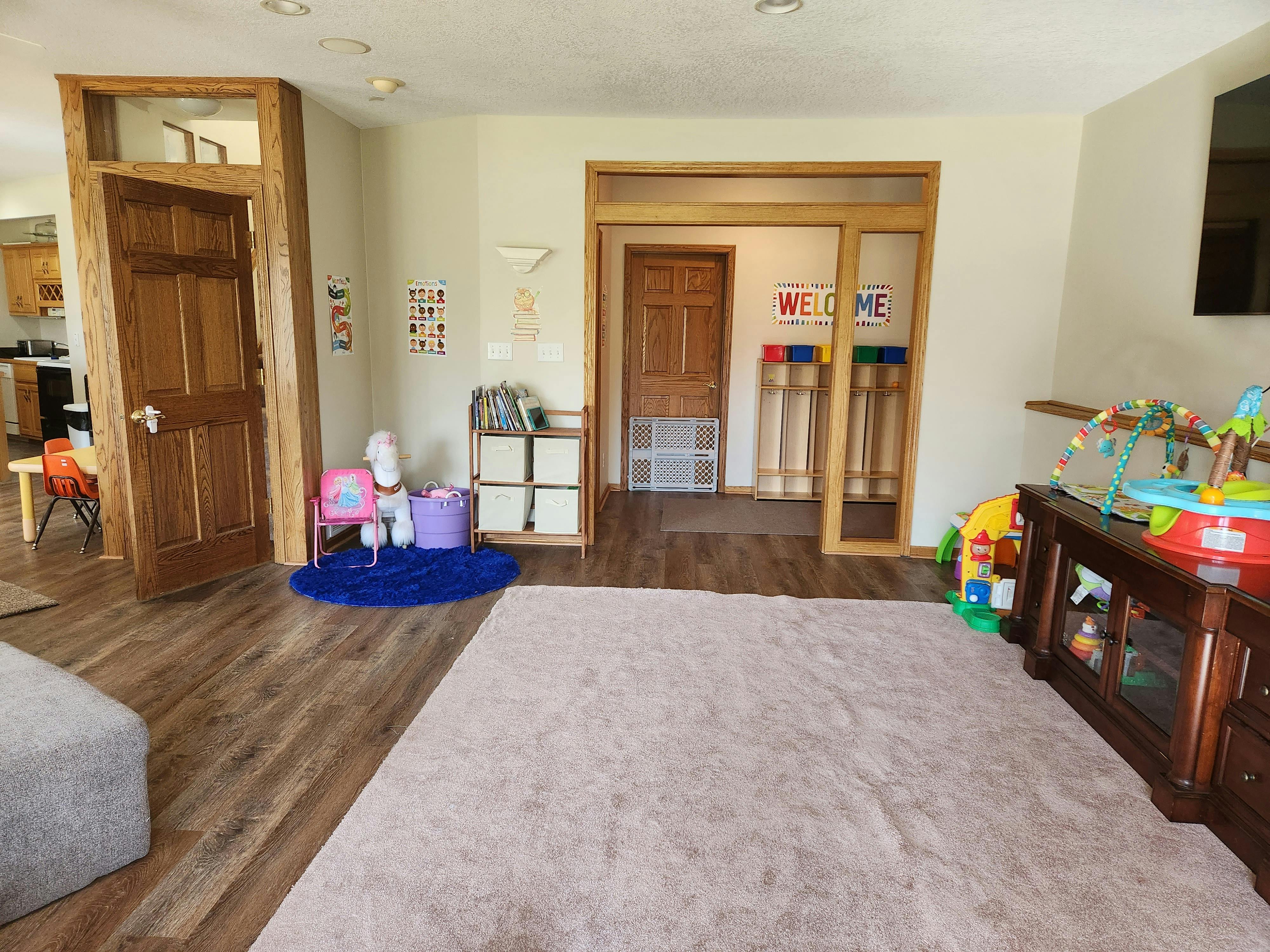 Living room with wood floors, light rug, and children's toys