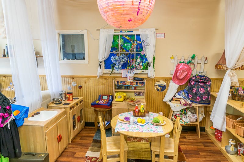 Playroom with a small table and chairs, toy kitchen, and dress-up clothes