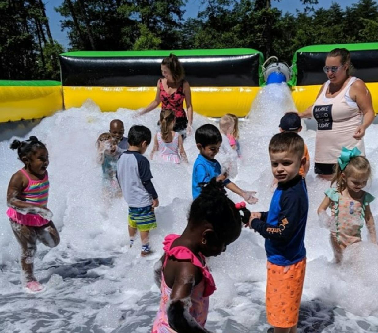 People and children playing in a foam pit outdoors