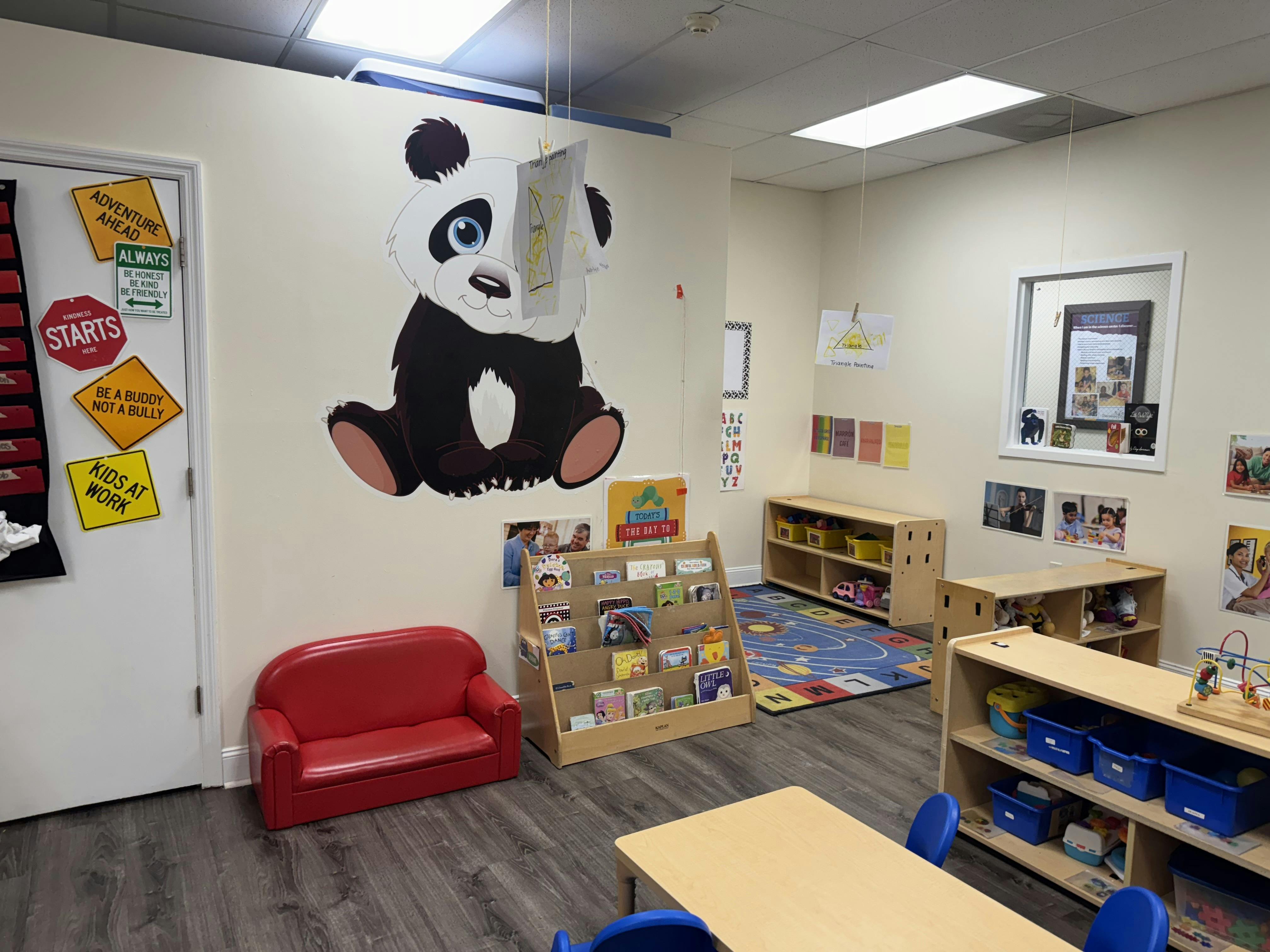 Classroom with a panda wall decal, red couch, and bookshelves
