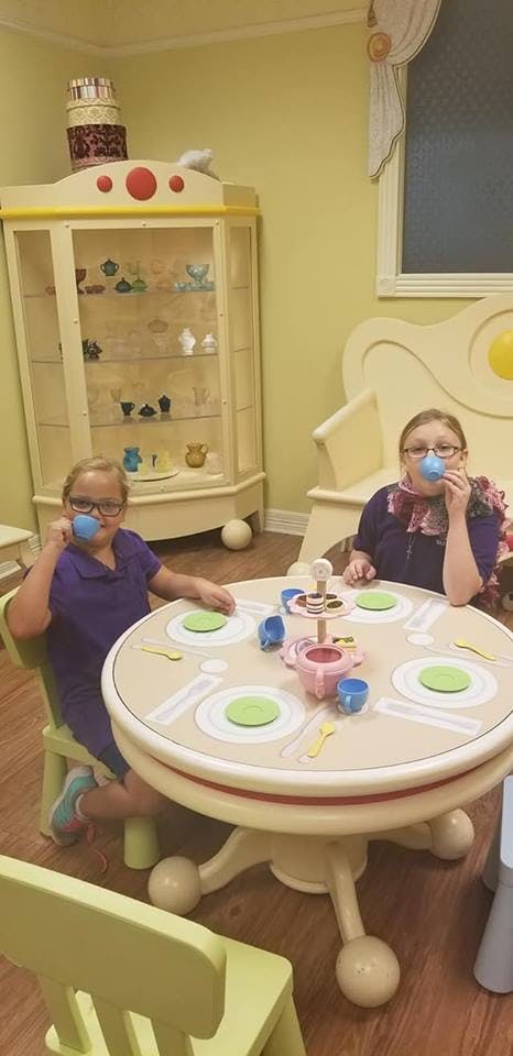Two children playing with a tea set at a small table
