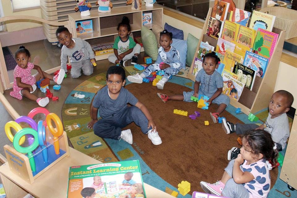 Children playing with toys on a rug in a classroom
