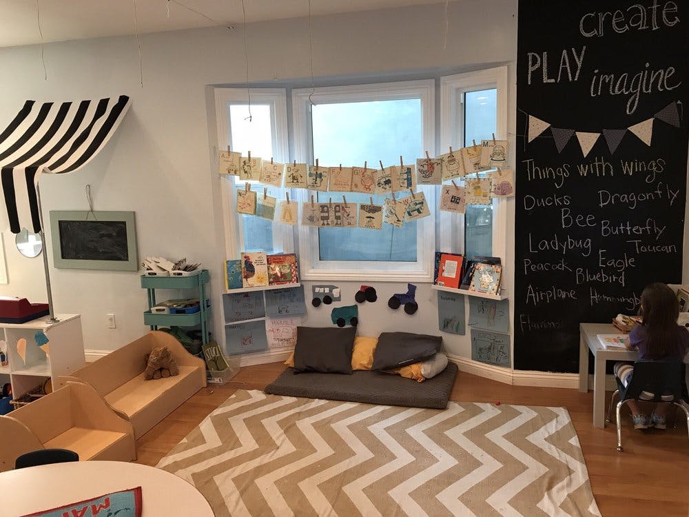 Classroom with a child at a desk, a large window, and a chalkboard wall