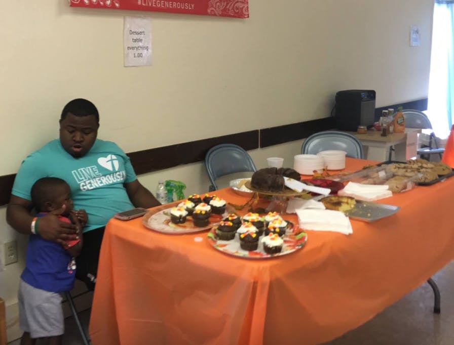 Person and child next to a table with cupcakes and other food