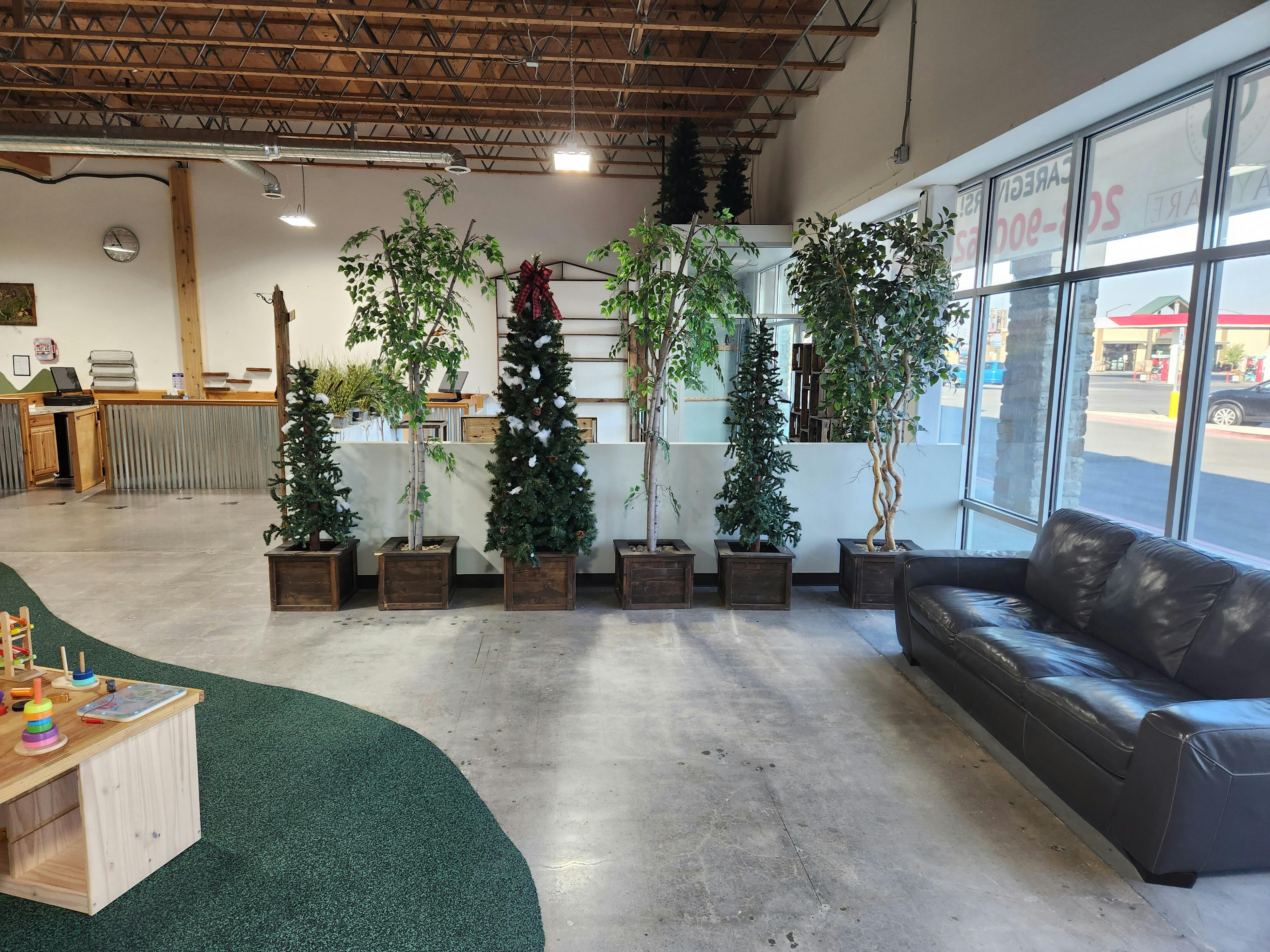 Indoor waiting area with a sofa, potted plants, and large windows