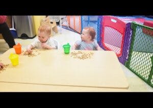 Two children playing with small objects at a table