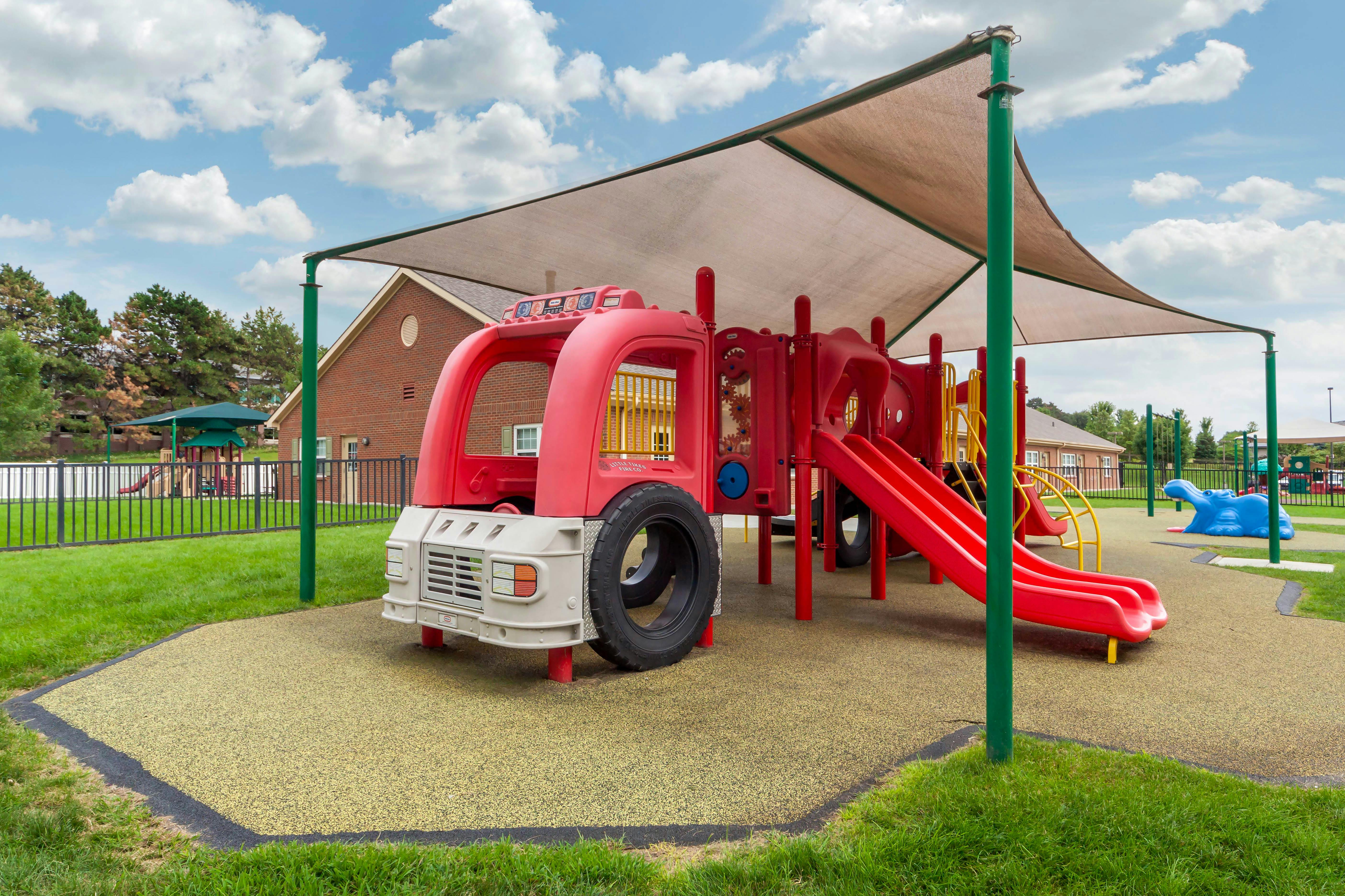 Red and yellow playground with slides and a fire truck toy