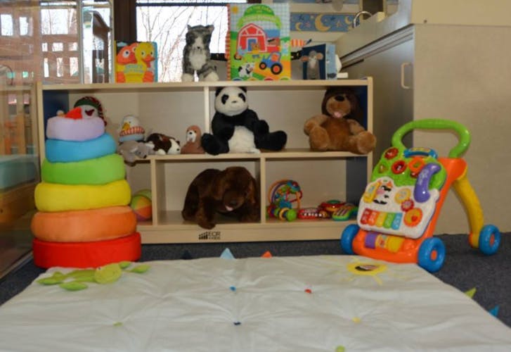 Children's toys including a stacking ring tower, stuffed animals, and a baby walker