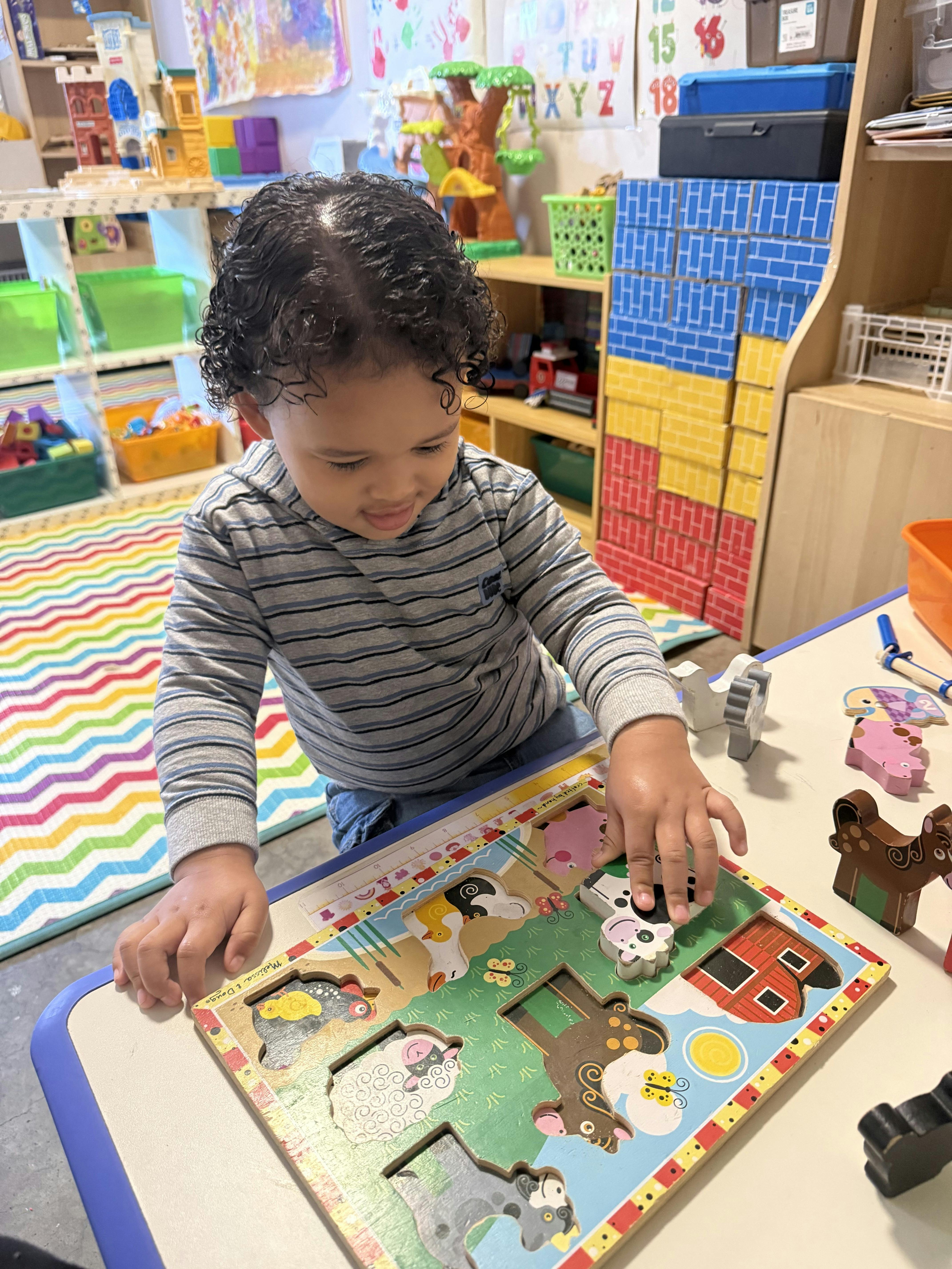 Child playing with a wooden animal puzzle at a table
