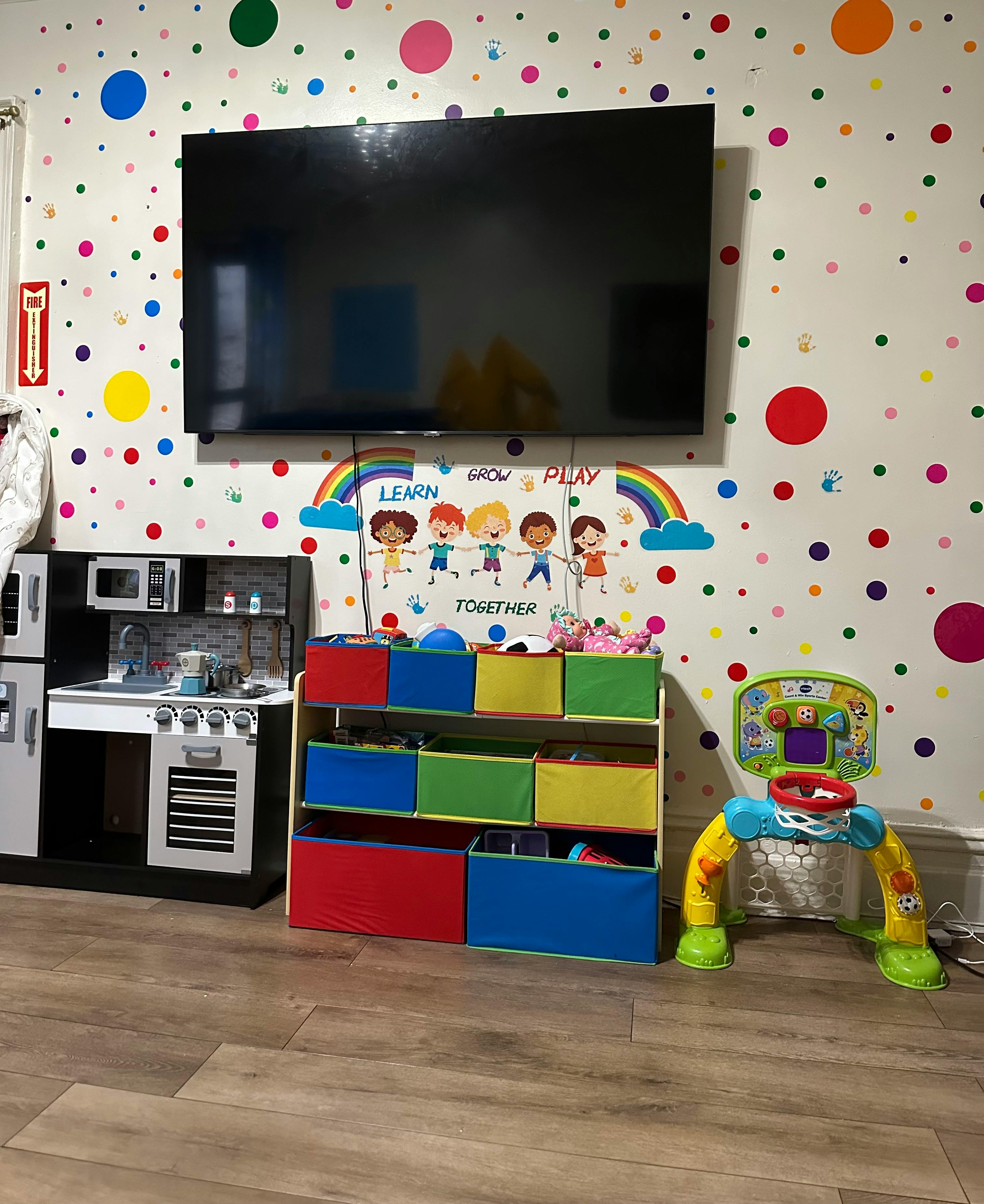 Playroom with polka dot wall, toy kitchen, and storage bins