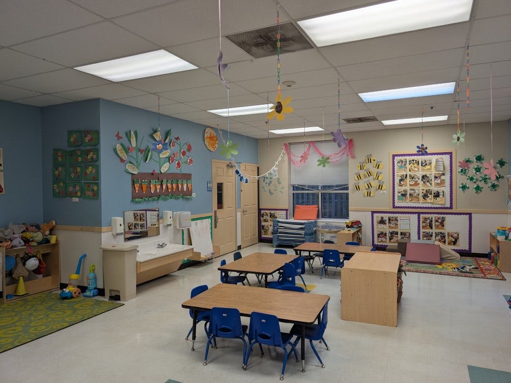 Empty colorful preschool classroom with tables, chairs, and children's artwork