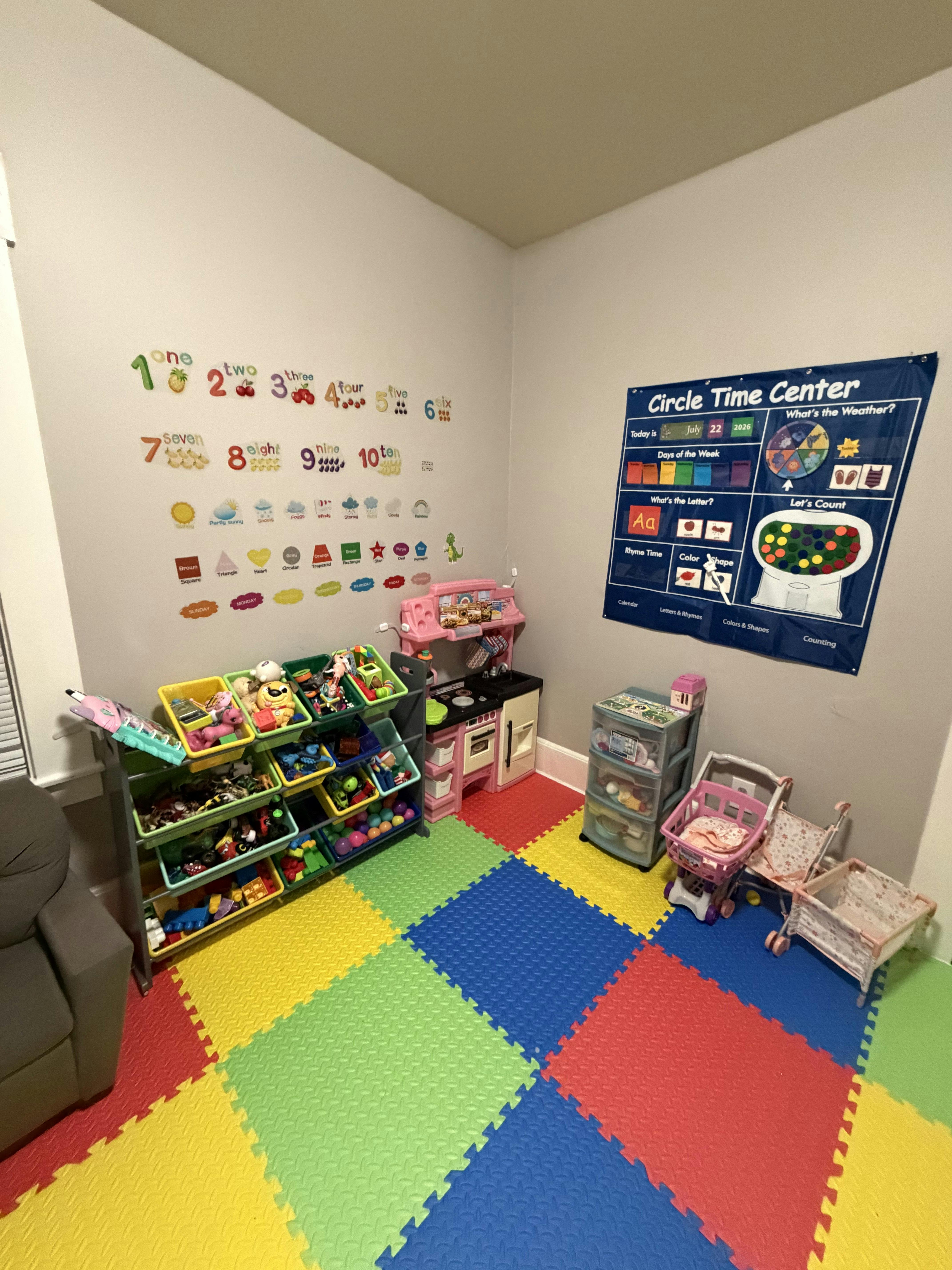 Playroom corner with educational wall posters, toy storage, and play kitchen