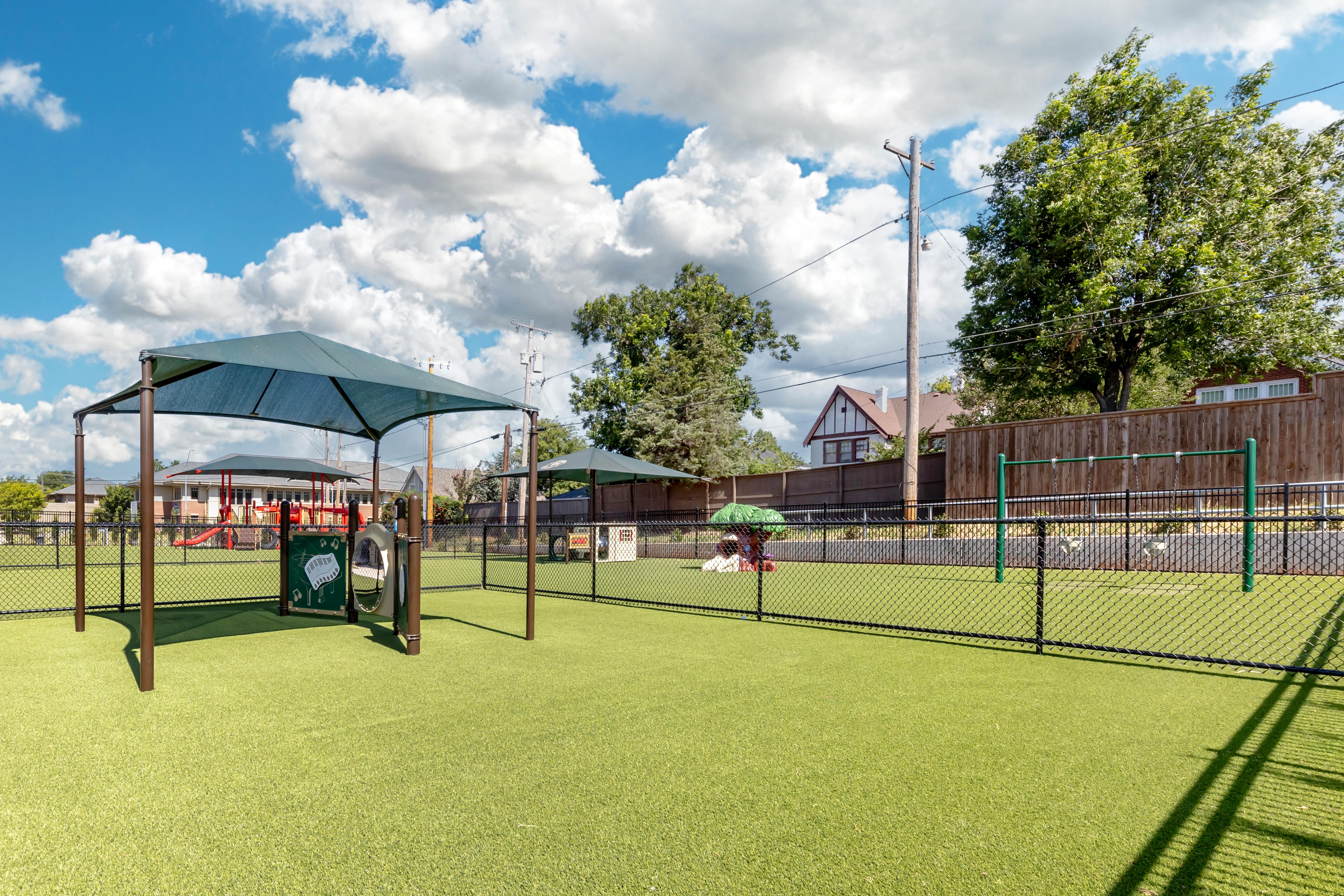 An outdoor playground area with green turf and various play equipment