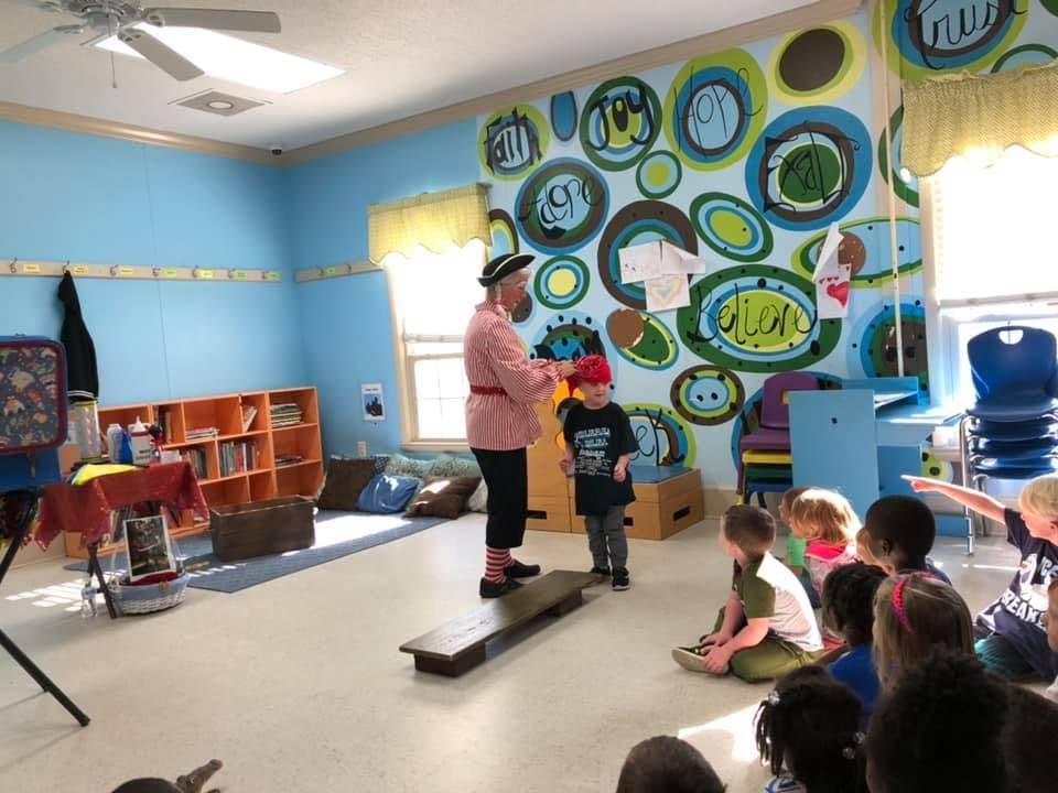 Person in costume interacting with a child in a classroom with other children watching