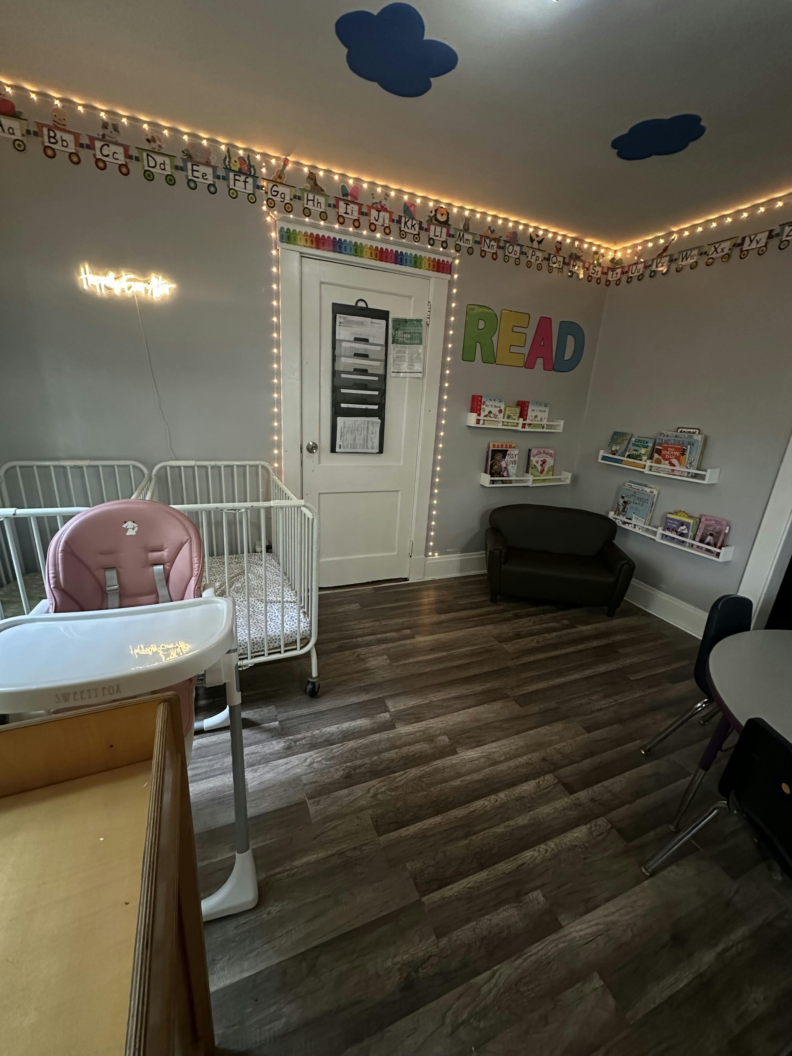 A room with a crib, high chair, and shelves of books
