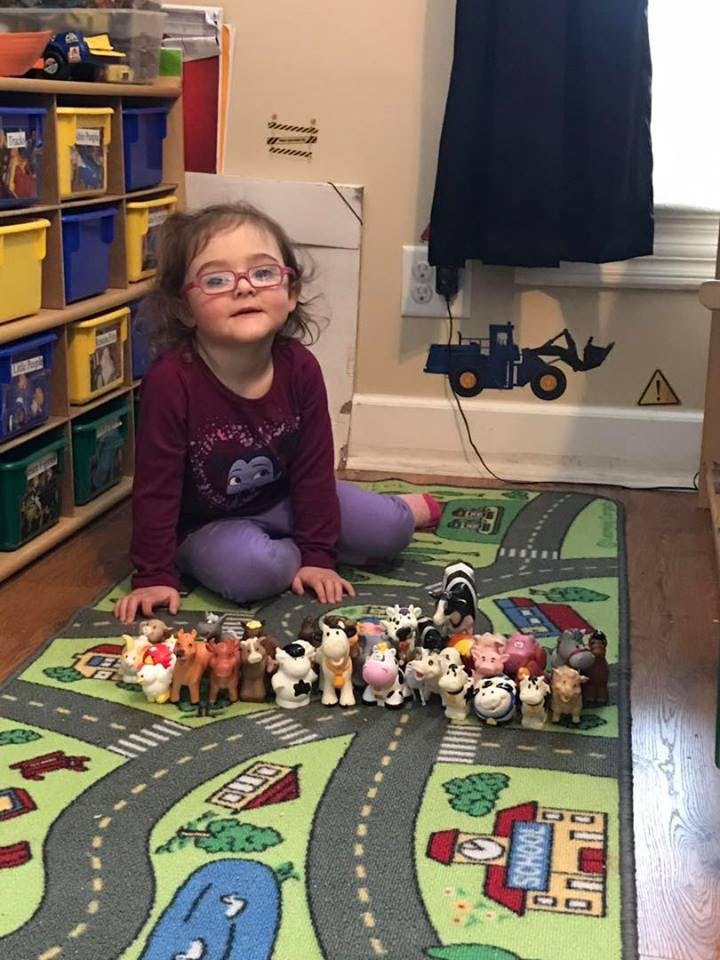 Child sitting on a rug with toy farm animals