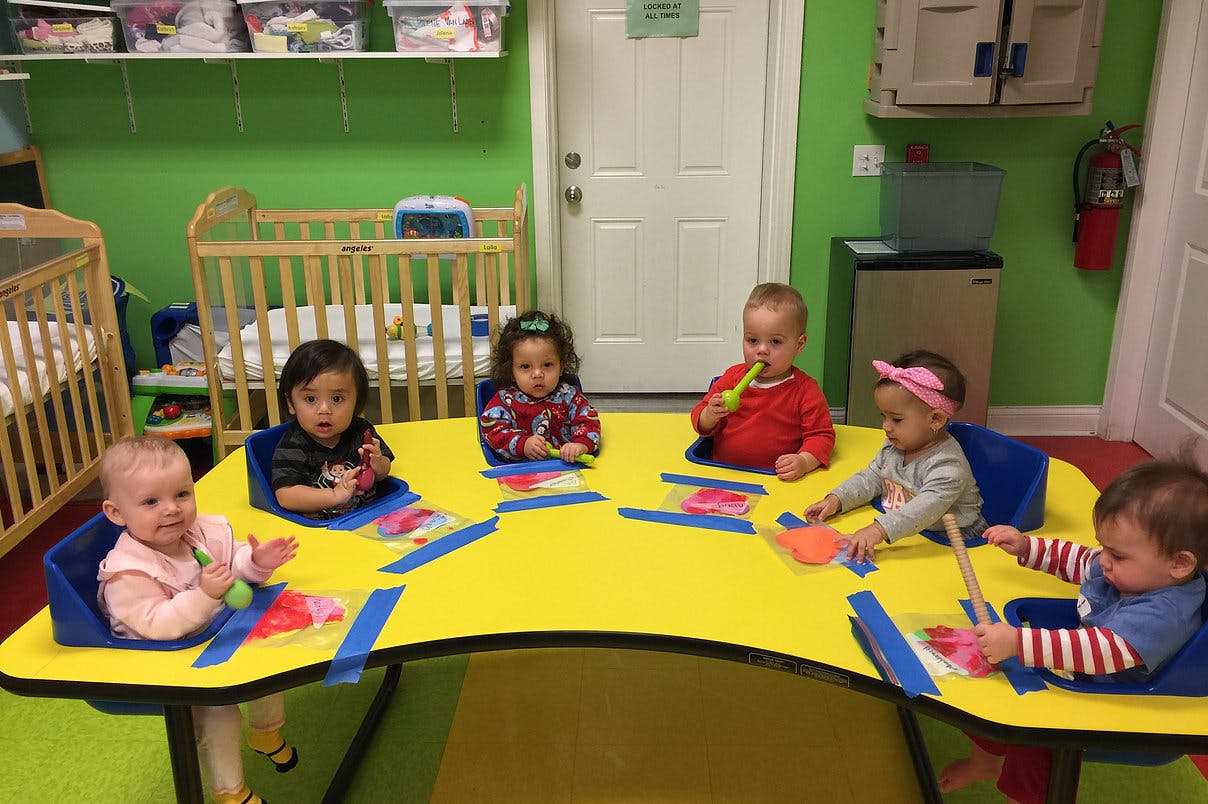 Five children sitting at a yellow table