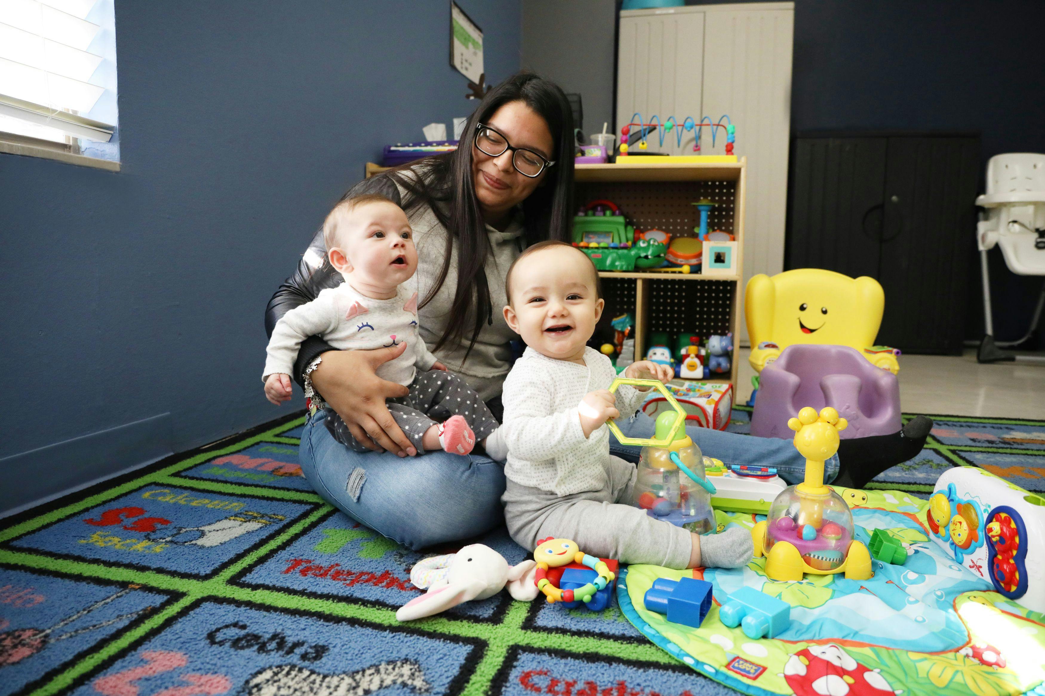 Person sitting on floor with two children and toys