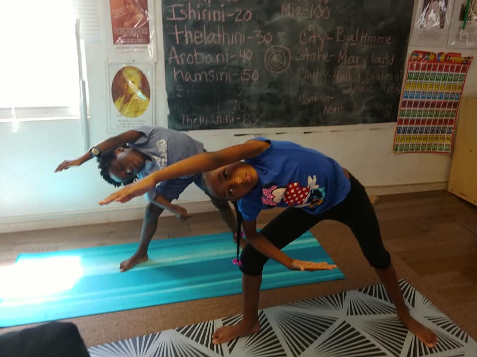 Two children doing yoga poses in a classroom