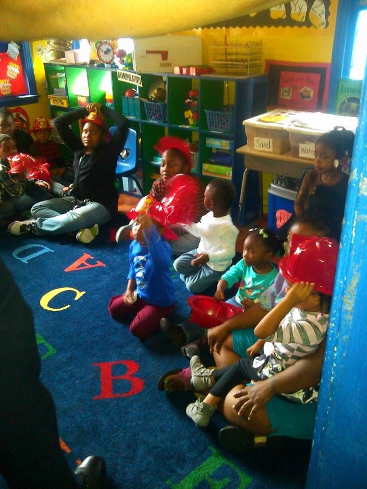 Children sitting on a blue alphabet rug in a classroom