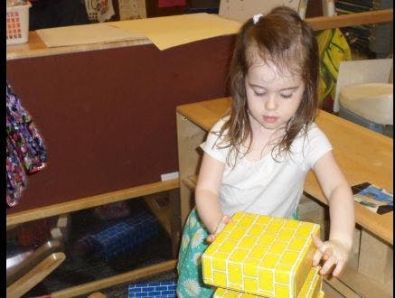 Child stacking yellow blocks in a classroom