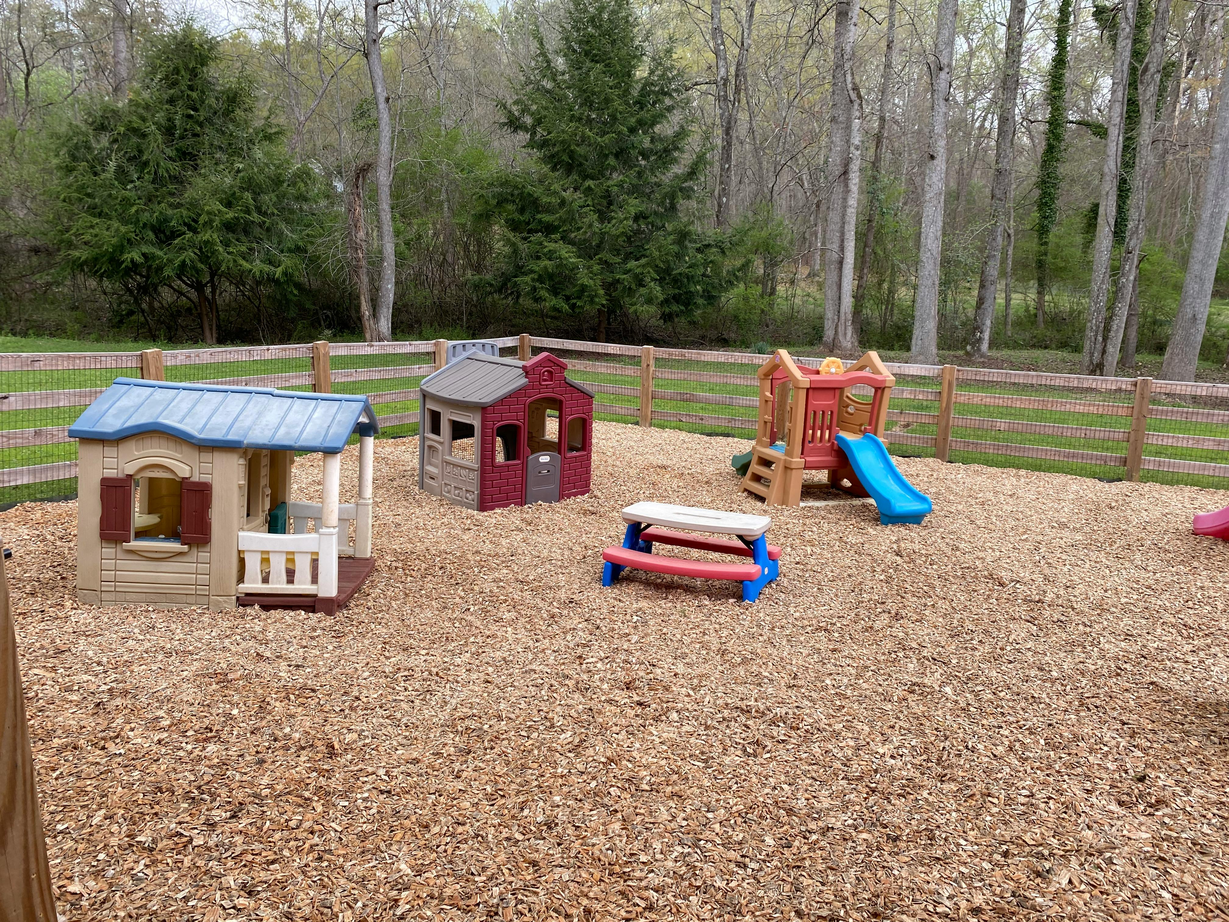 Playground with playhouses, slide, and picnic table on wood chips