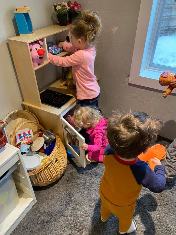 Three children playing with a toy kitchen set