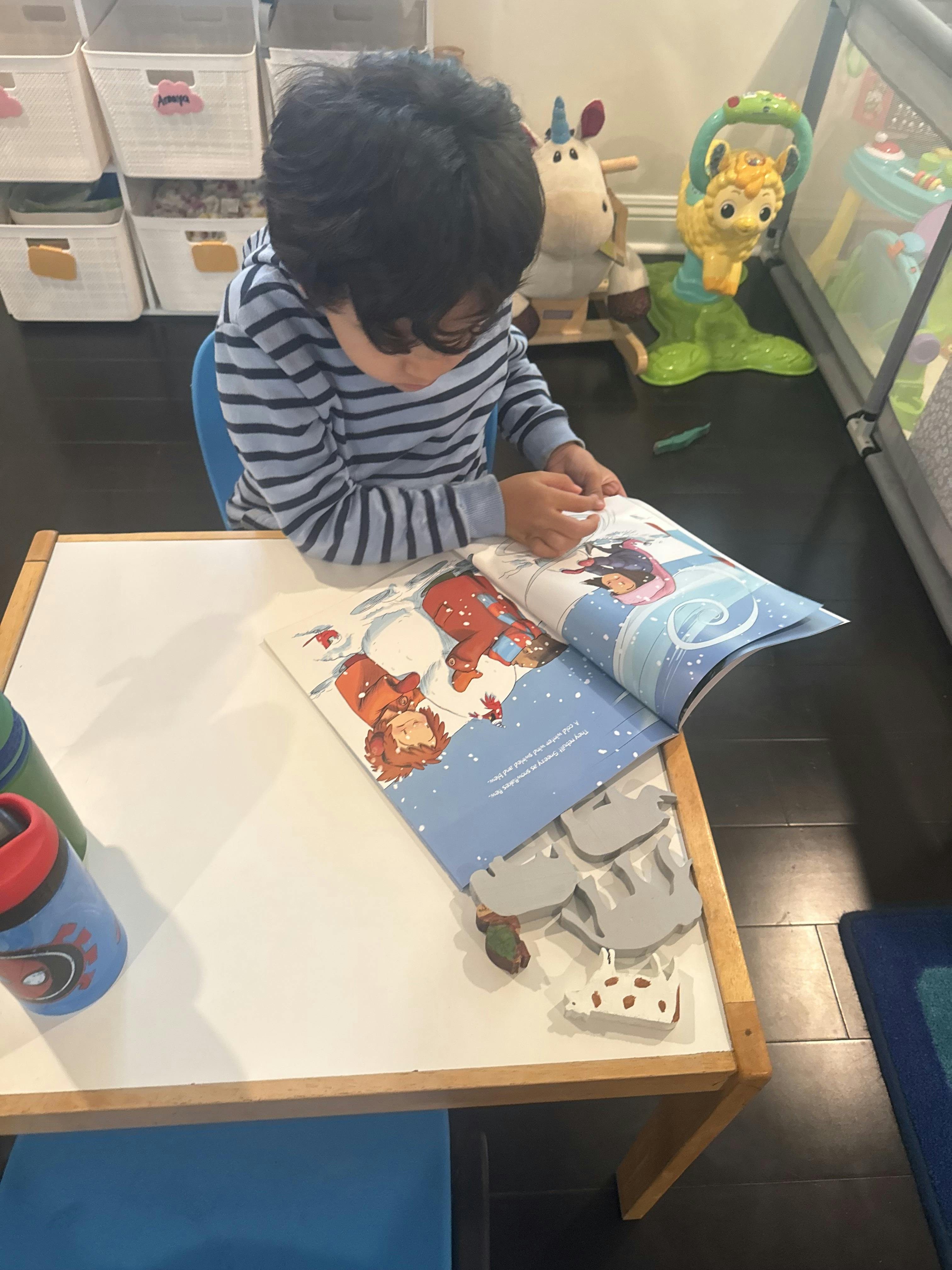 Child sitting at a table reading a book