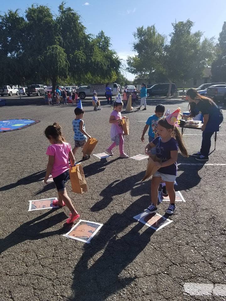 Children walking on squares on pavement, some holding bags