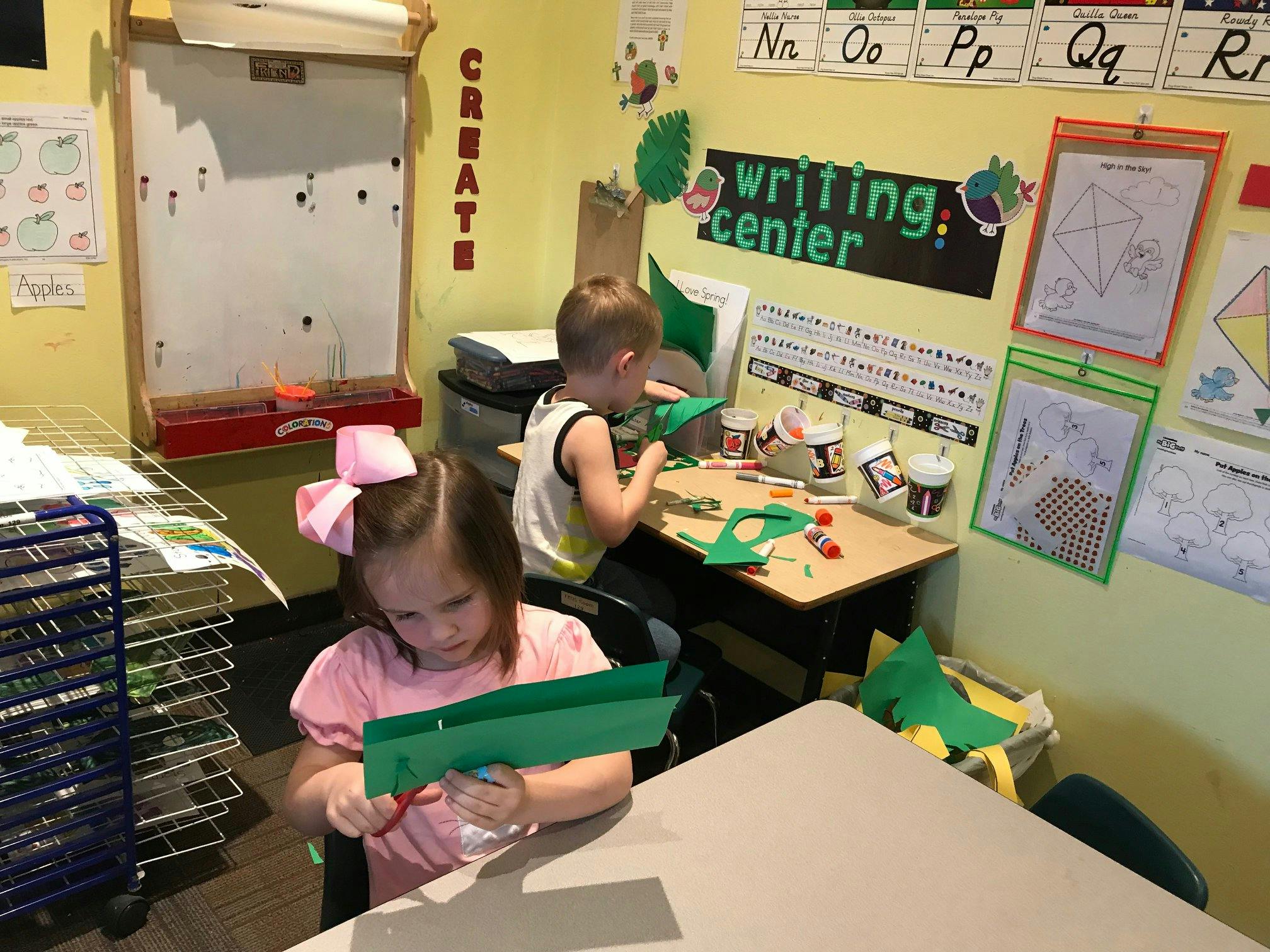 Two children cutting paper in a classroom