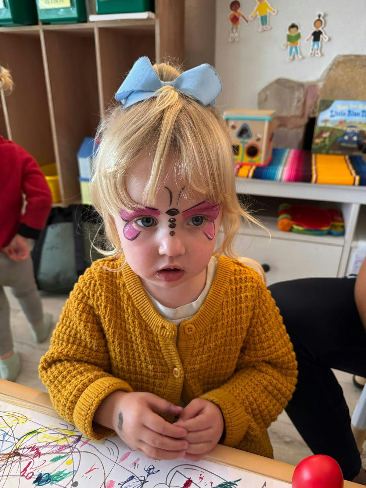 Child with butterfly face paint and a blue bow in their hair