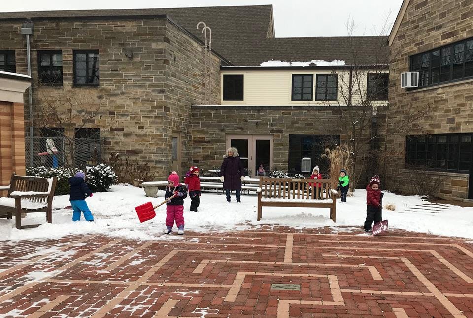 Children playing in snow with shovels in a courtyard