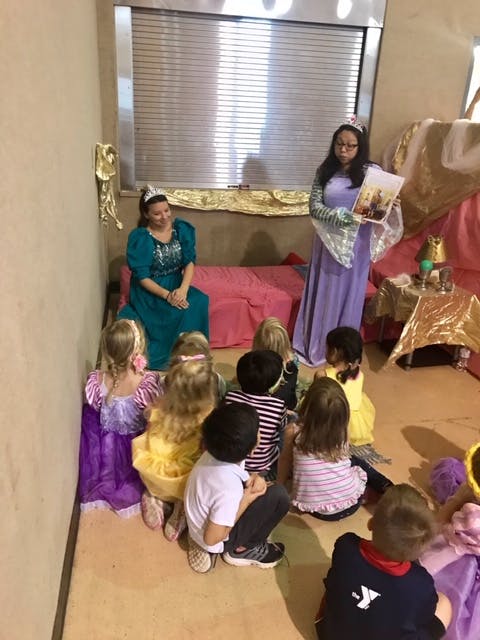Two people in costumes reading to a group of children sitting on the floor