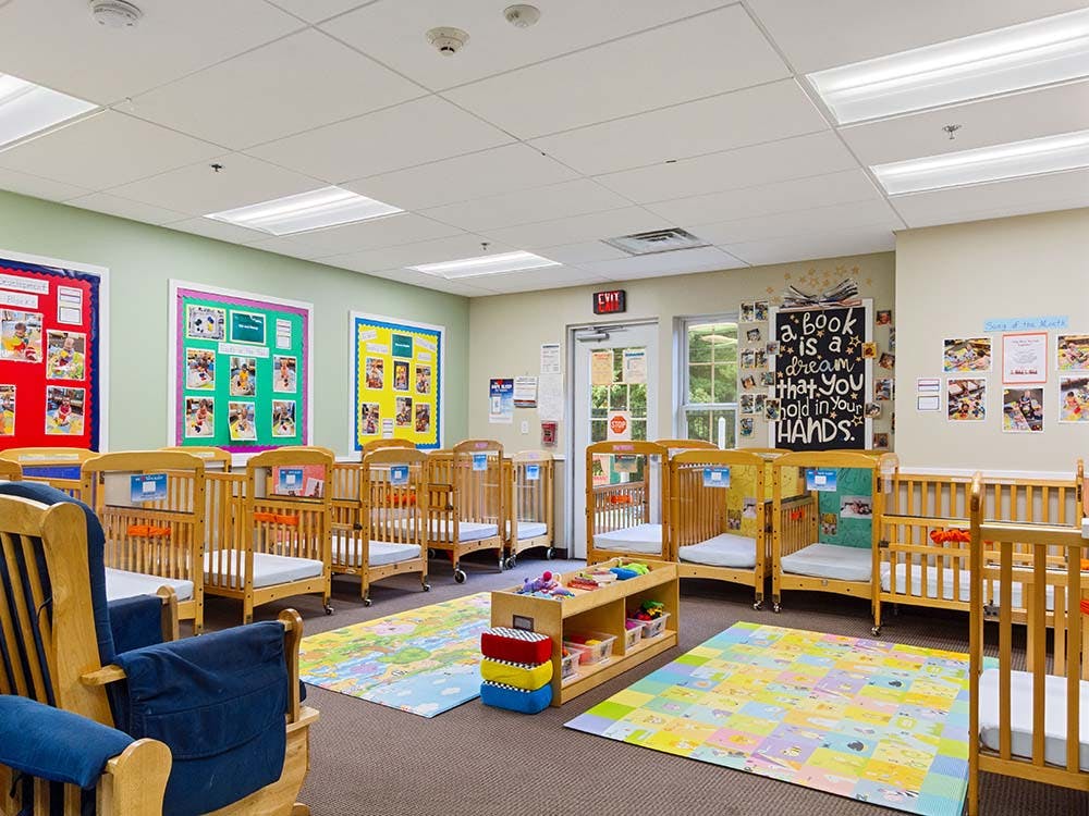 An empty nursery with multiple wooden cribs and two colorful play mats
