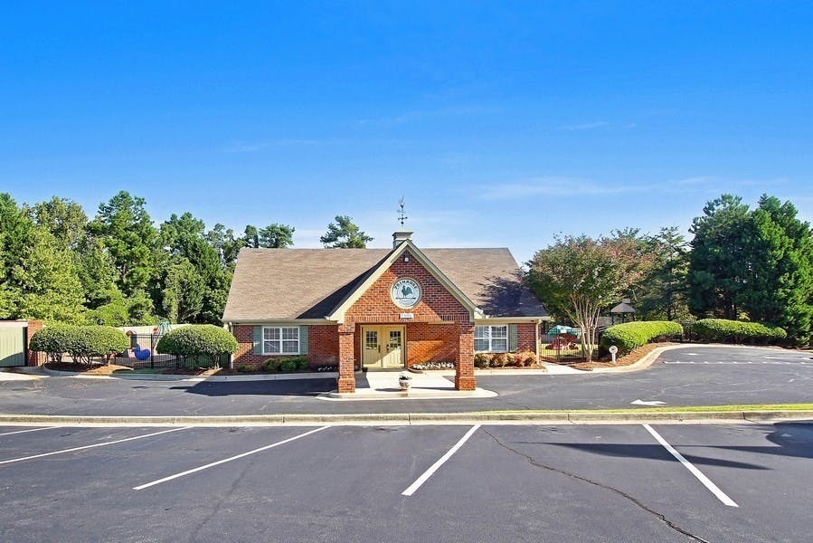 Brick building with a brown roof and a parking lot in front