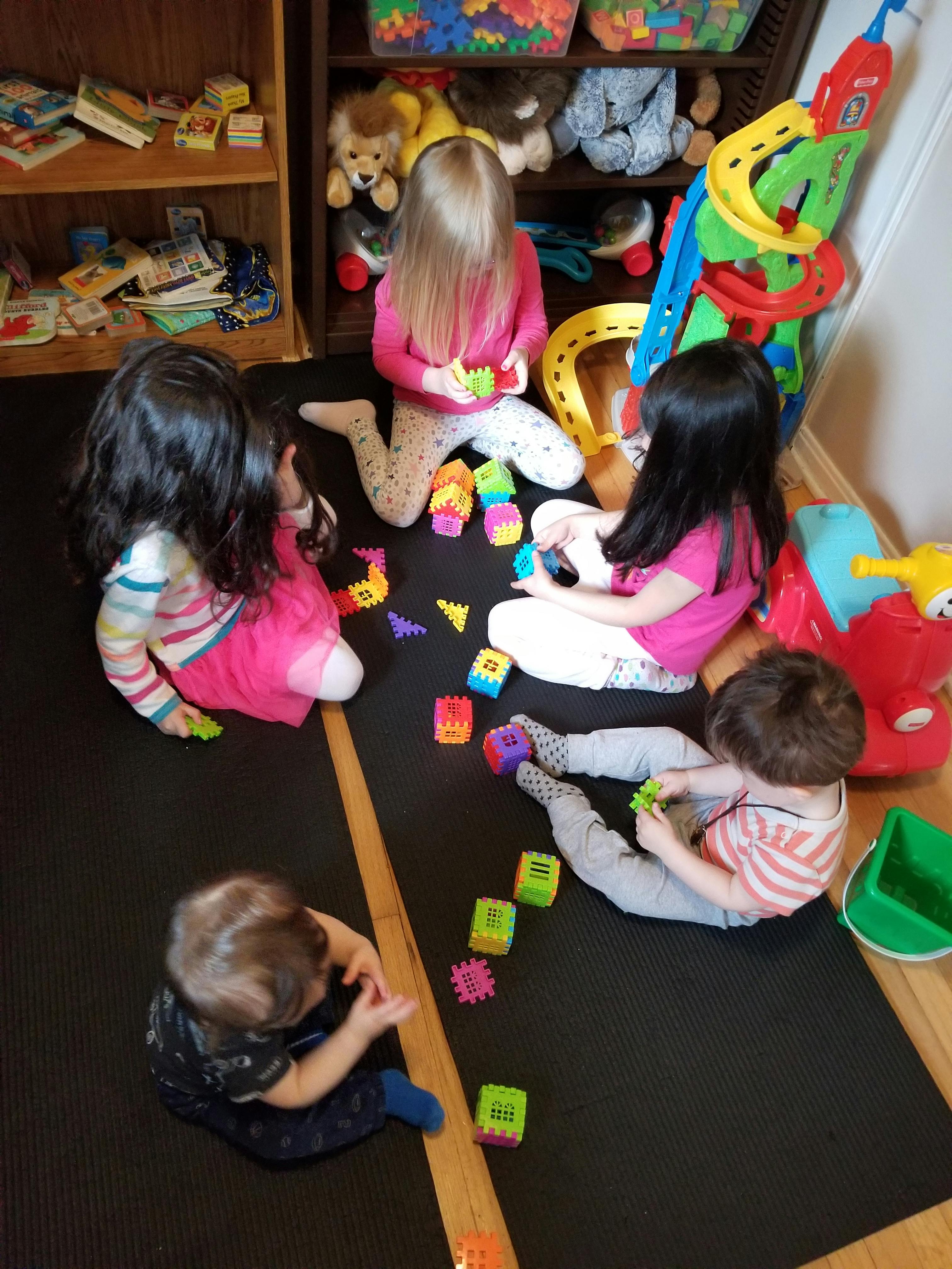 Children playing with colorful blocks on a mat in a classroom