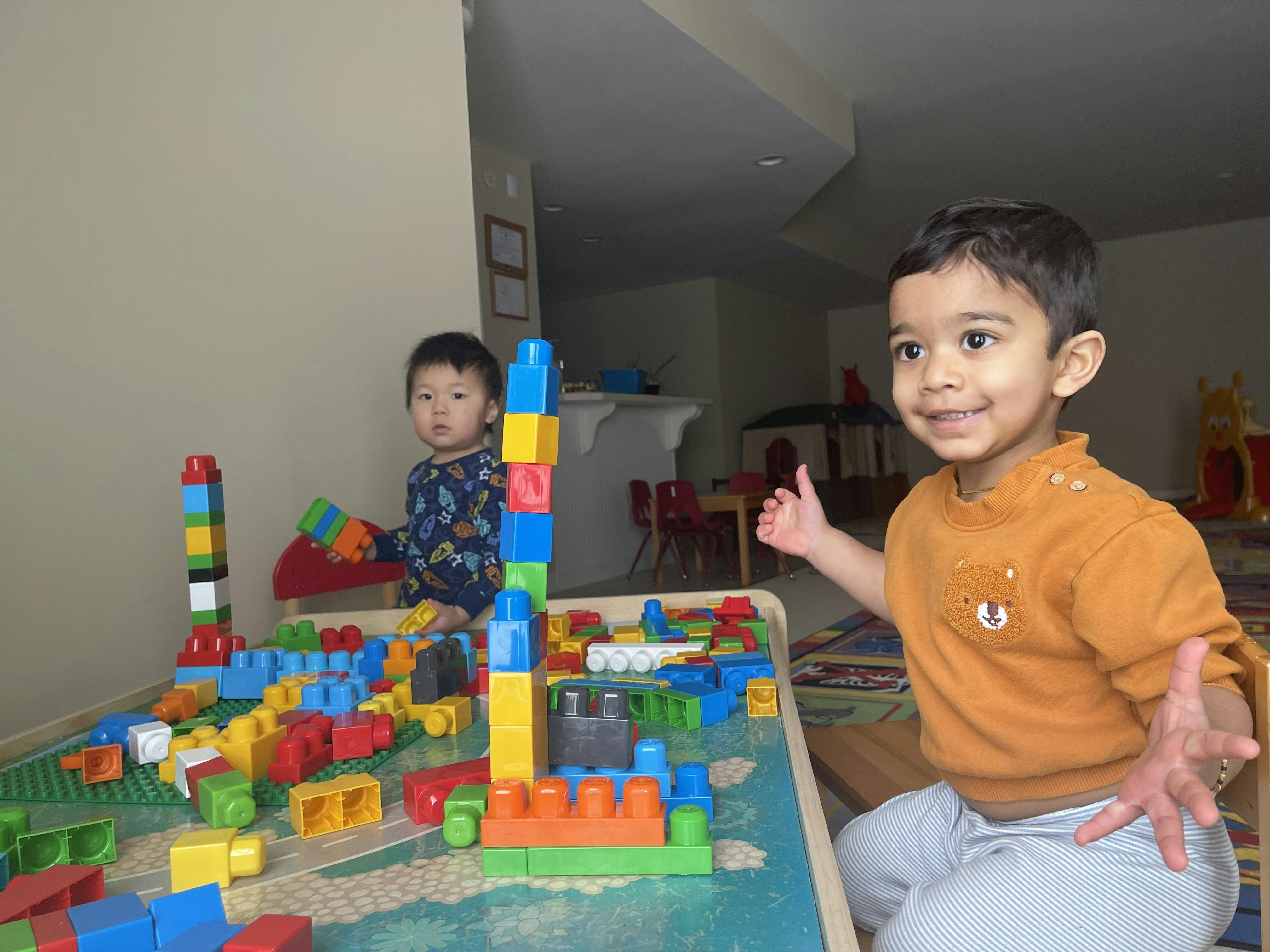 Two children playing with colorful building blocks at a table