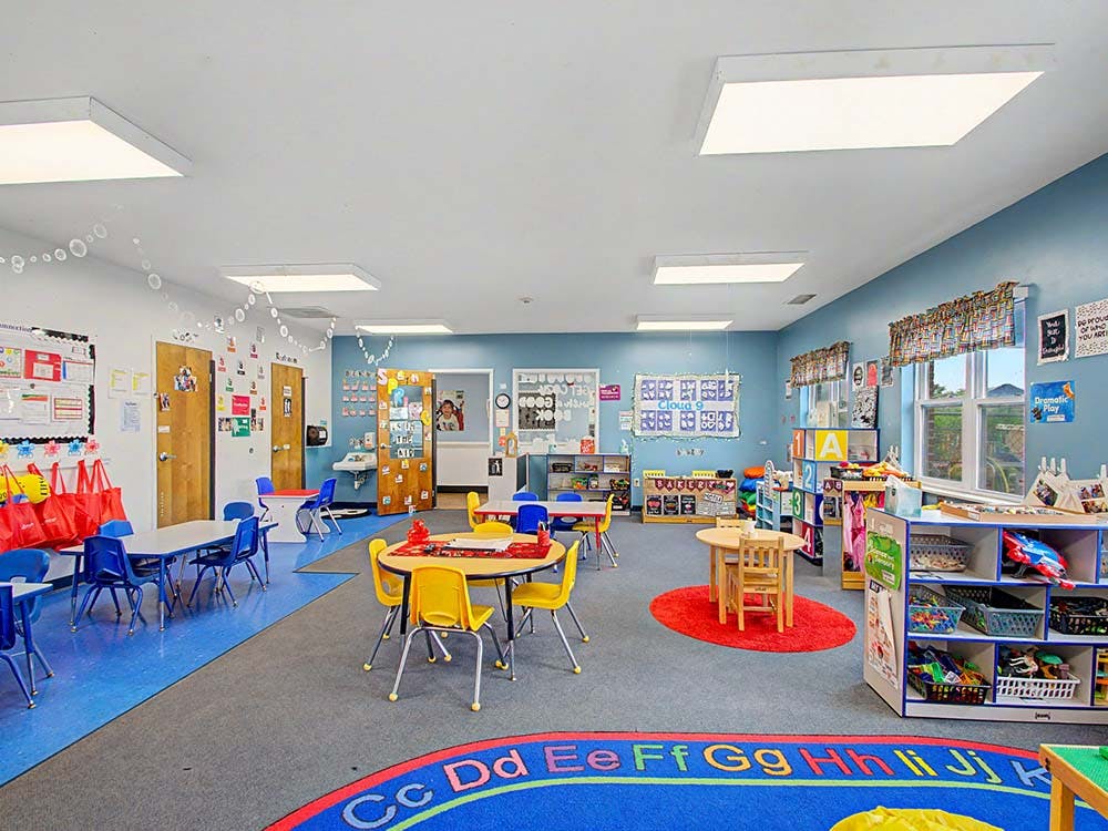 Colorful empty classroom with small tables and chairs
