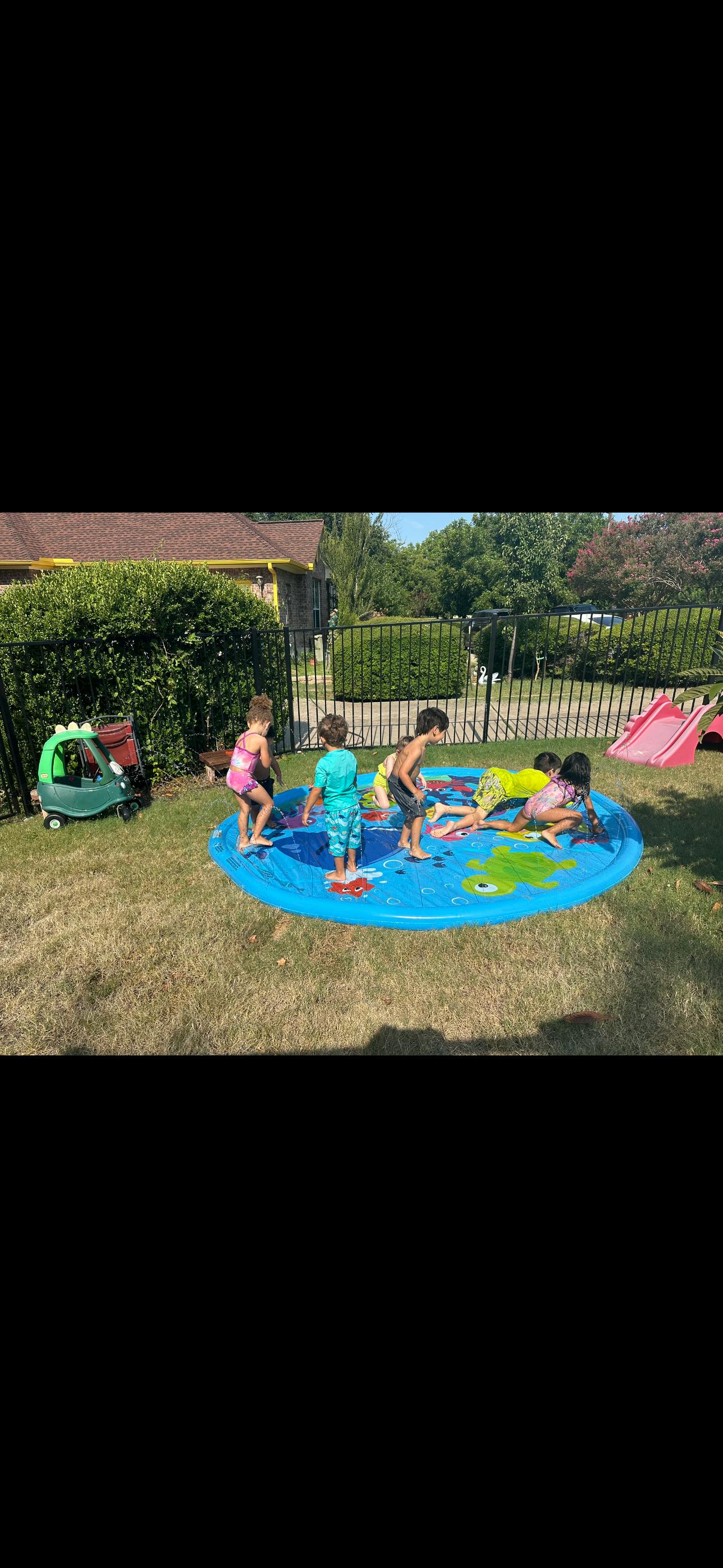 Children playing in a small blue inflatable pool in a grassy yard