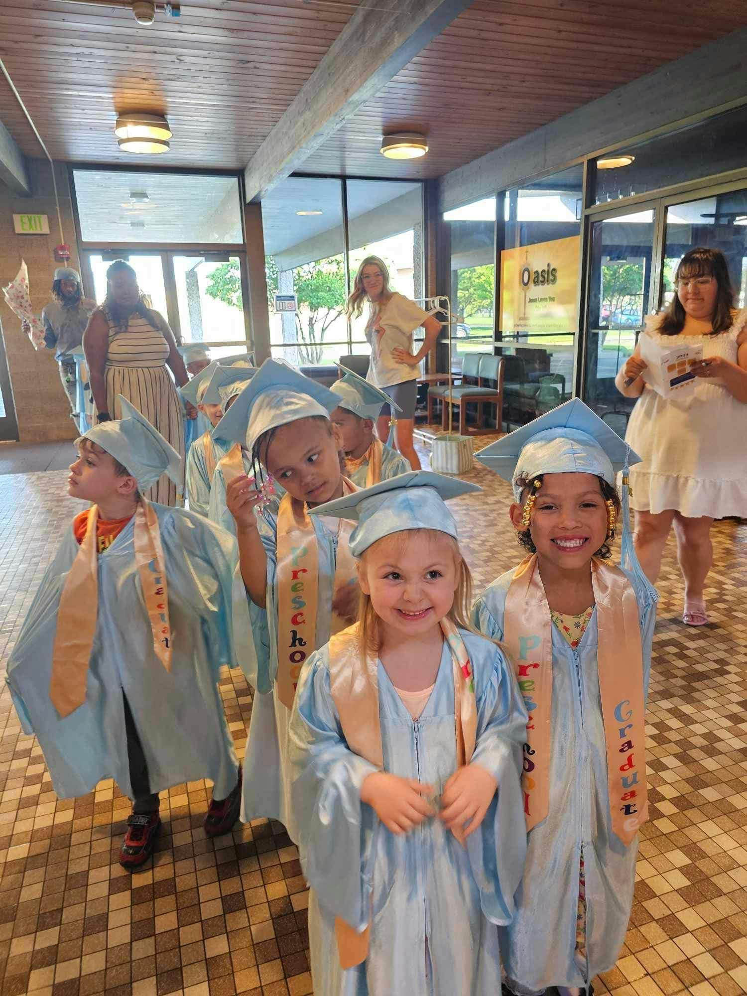 Children in light blue graduation caps and gowns