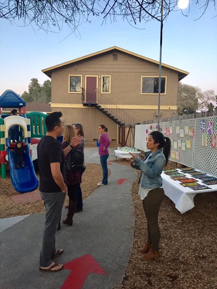 People gathered outdoors near a building and playground