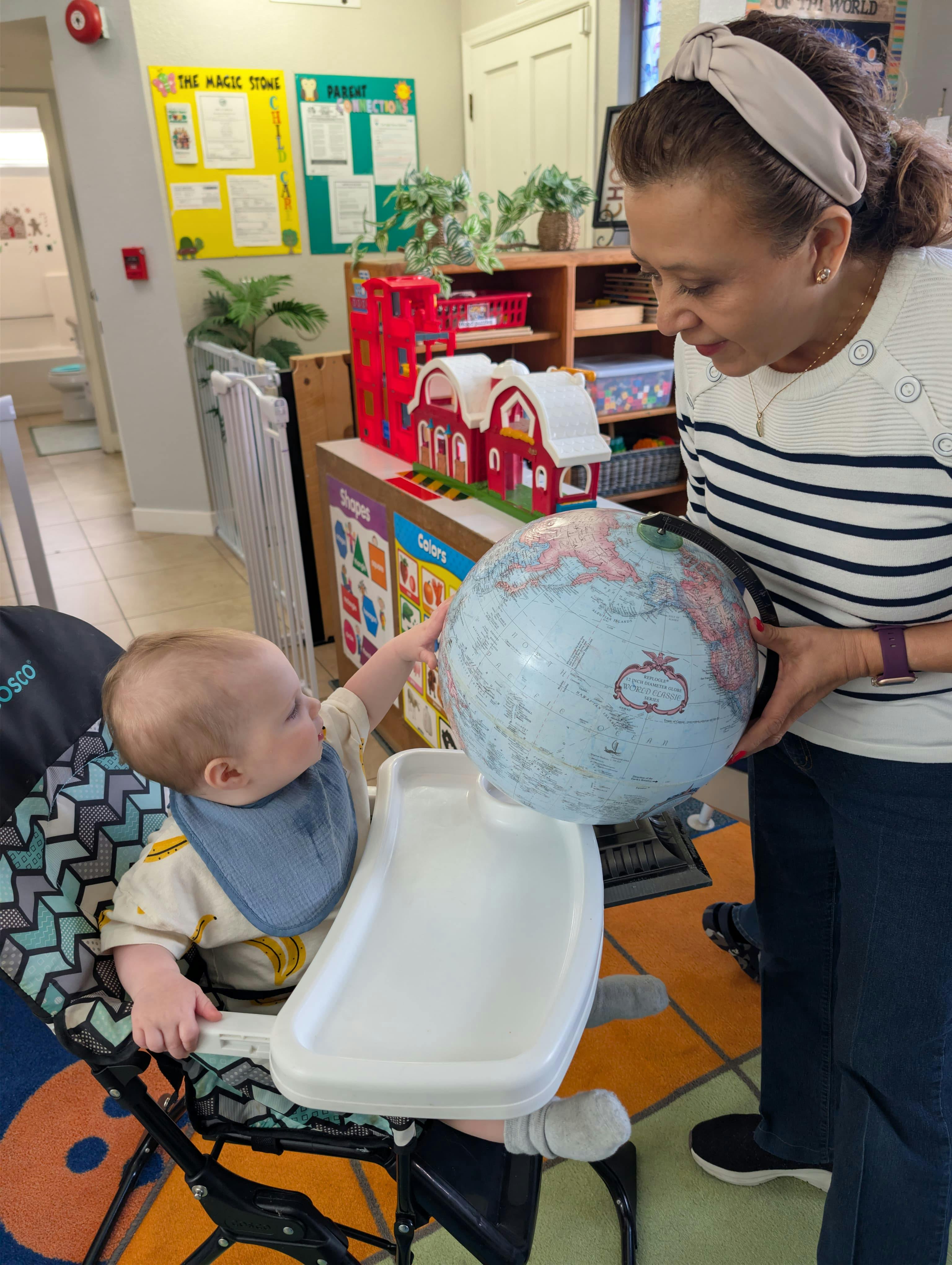 Adult and child in highchair looking at a globe