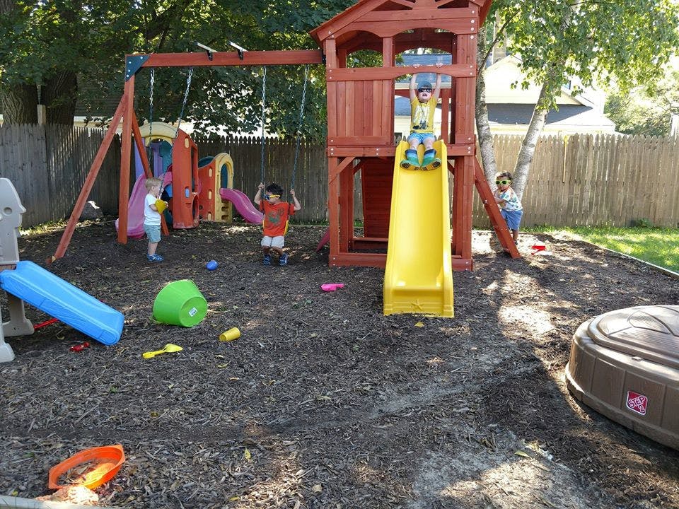 Children playing on a wooden playset with slides and swings