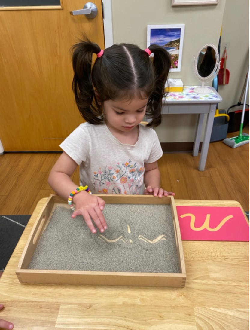 Child drawing in a sand tray with a finger