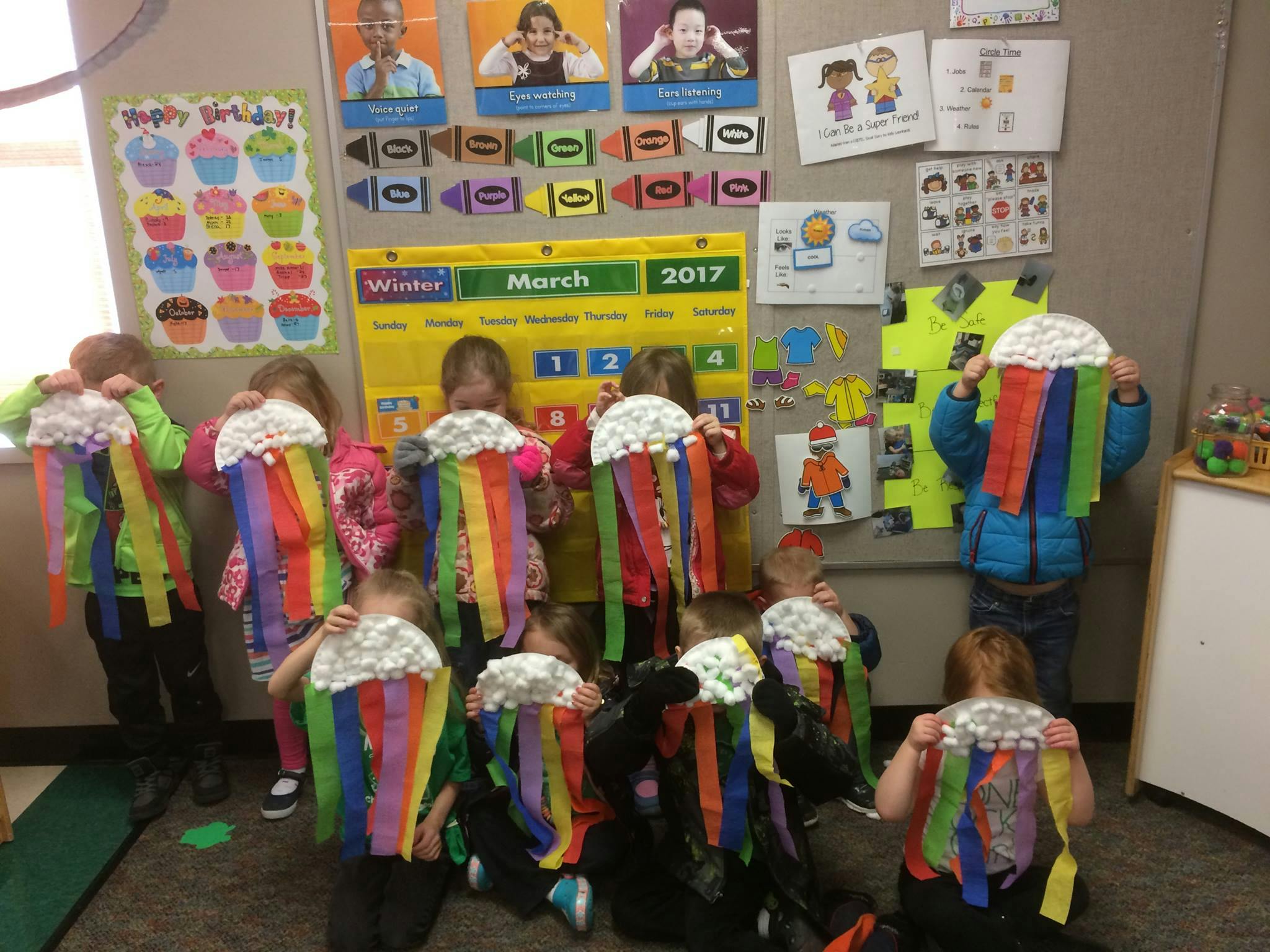 Children wearing rainbow streamer costumes in a classroom