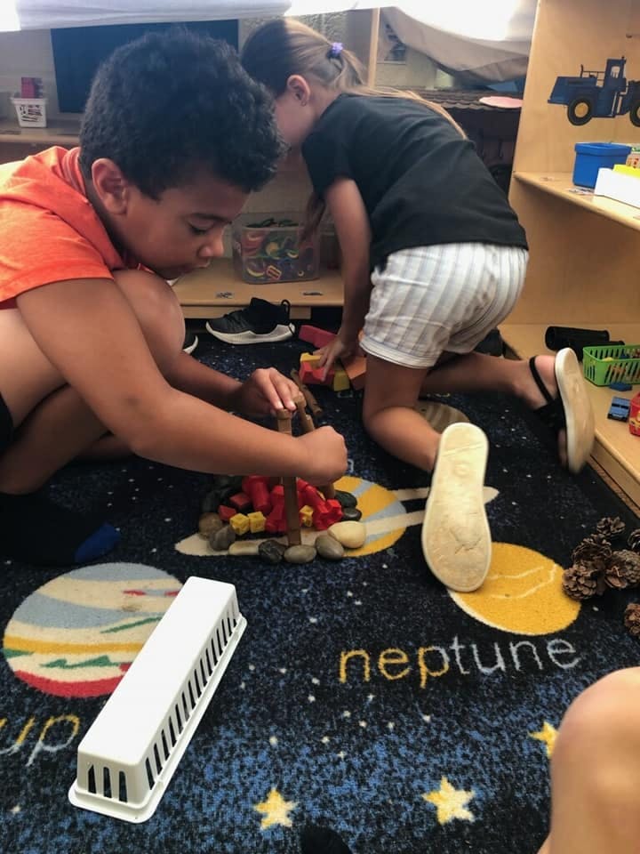 Two children playing with blocks on a rug