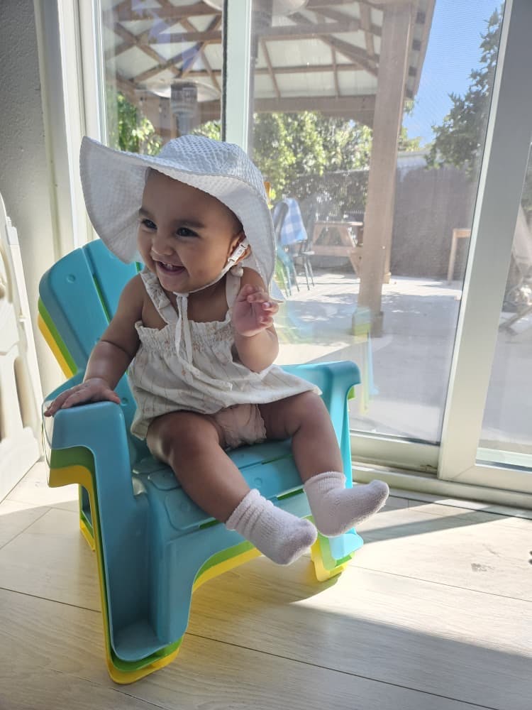 Child in a sun hat sitting in a small chair