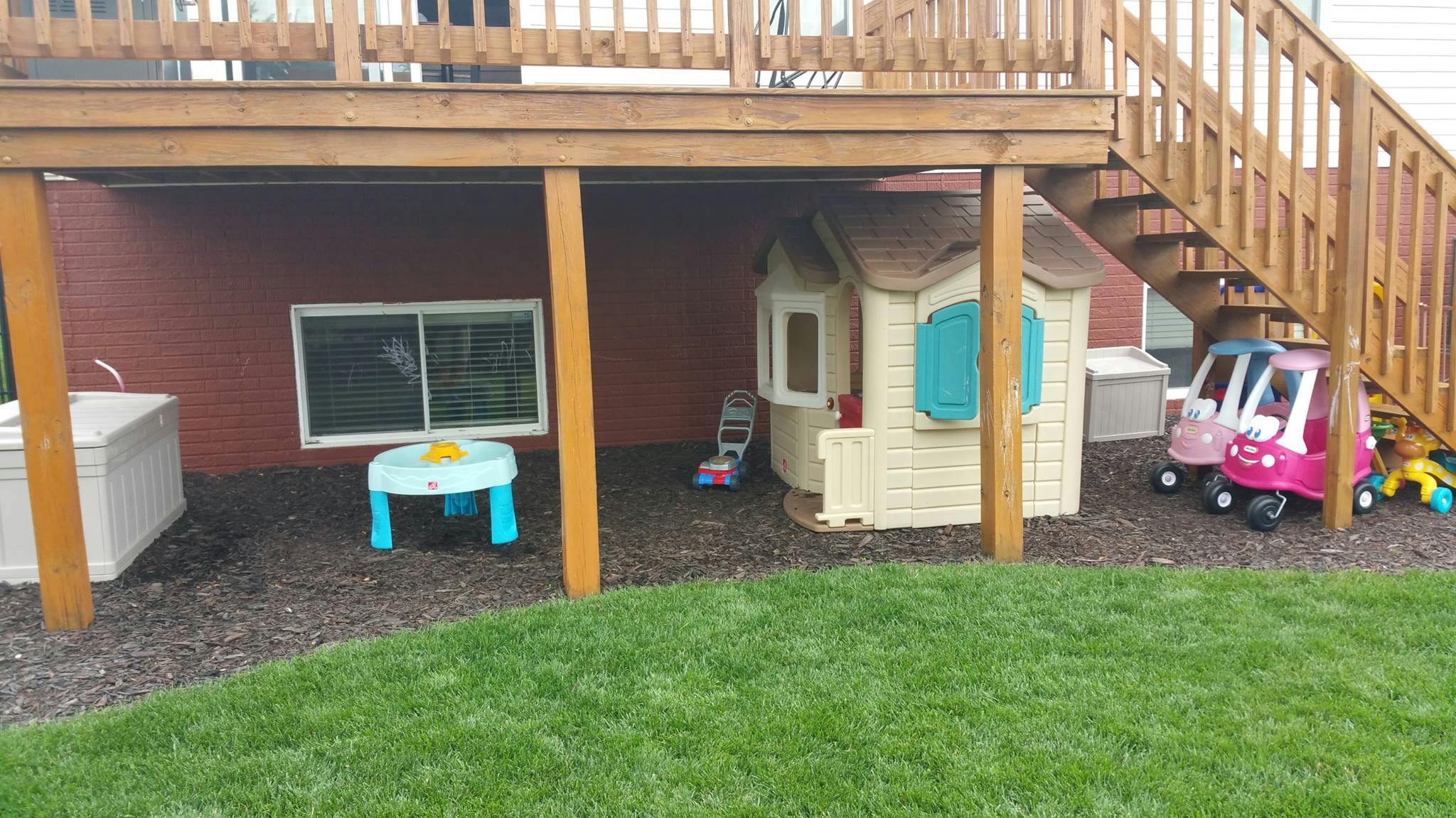 Play area under a deck with a playhouse and toy cars