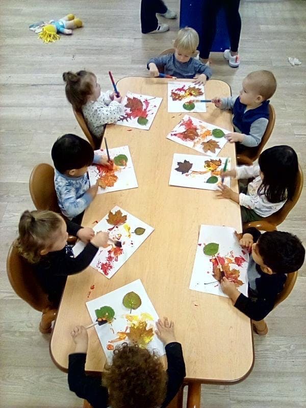 Children painting leaf prints at a table